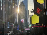 the sun is shining on a busy city street