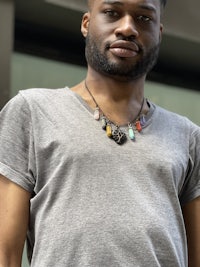 a black man wearing a gray t - shirt and a necklace