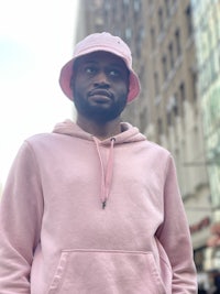 a man in a pink hoodie standing in a city