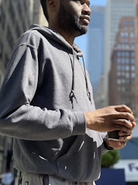 a man in a gray hoodie standing in a city