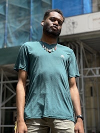 a man in a green t - shirt standing in front of a building